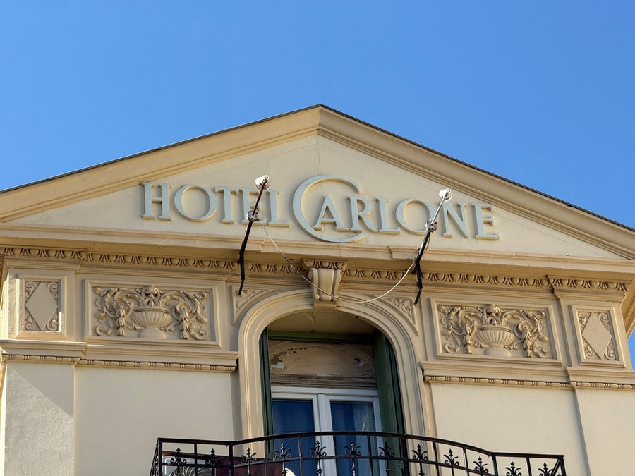Fronton « Hôtel Carlone » en lettres ornées, sous un ciel bleu