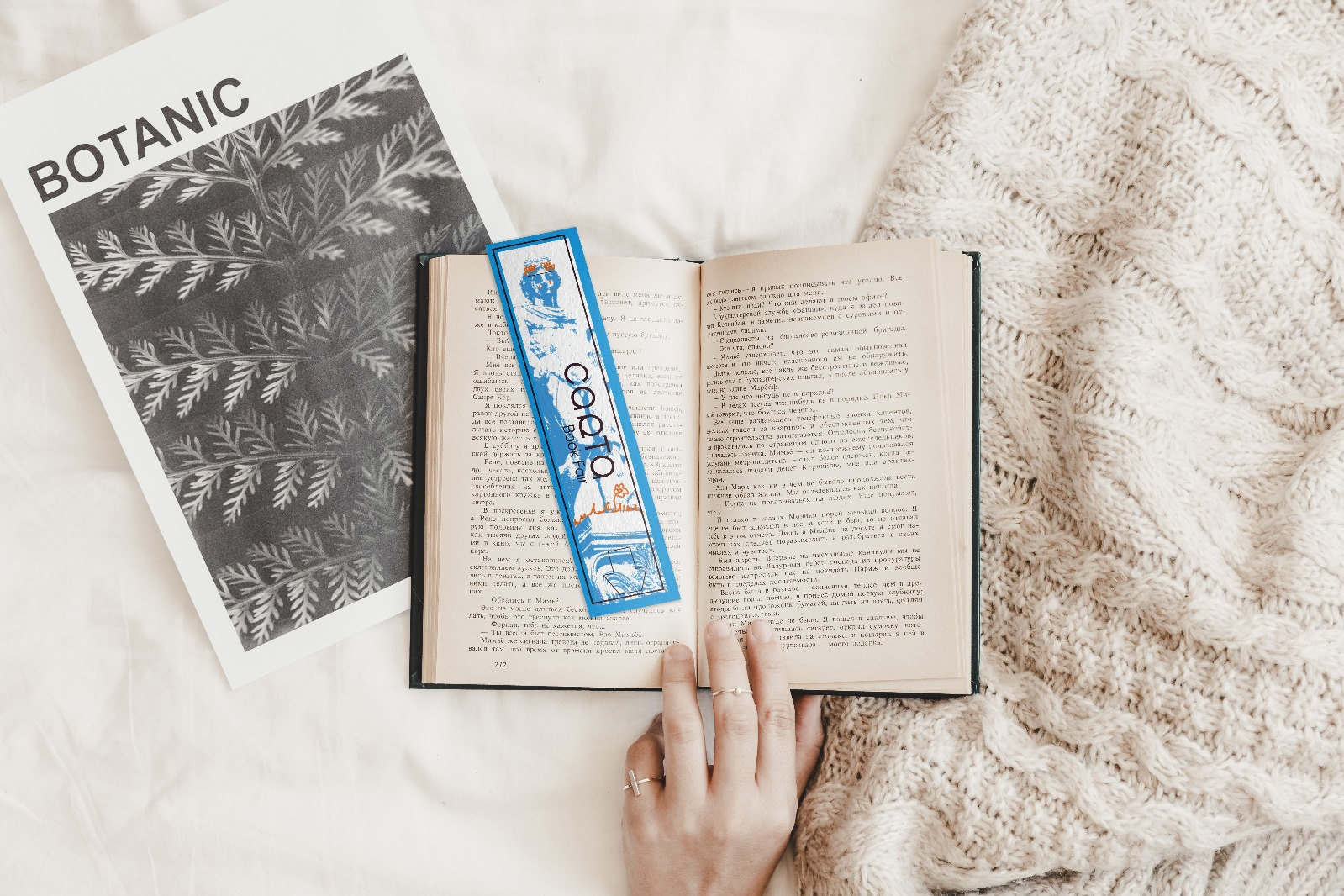 Un marque-page Carta posé dans un livre ouvert, sur un plaid