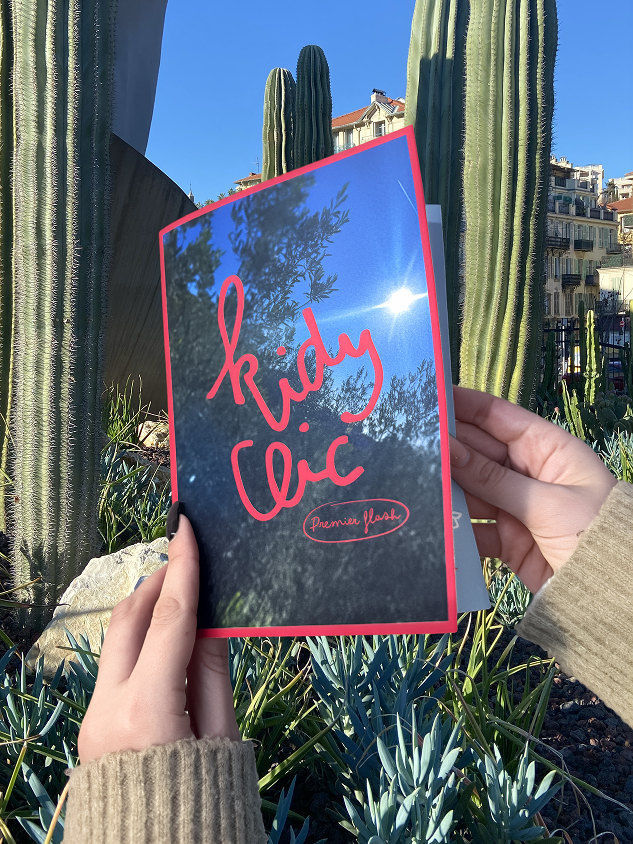 Le livret fermé, la couverture « kidy clic » sur une photo d’arbres, devant des cactus