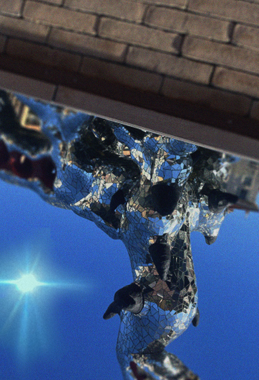 Une fontaine argentée photographiée à l’envers, le soleil en bas de l’image