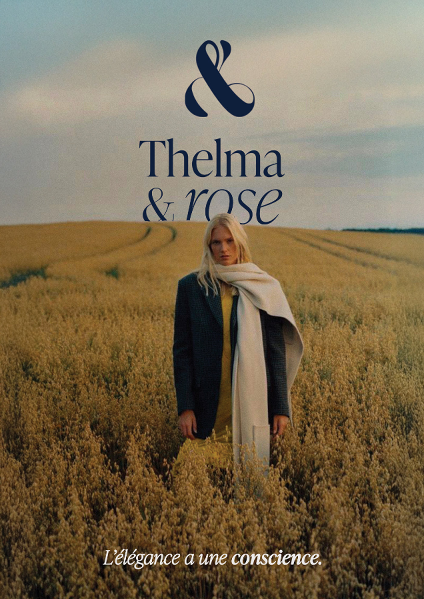 Affiche : une femme en manteau et écharpe crème dans un champ doré, logo navy en haut, « L’élégance a une conscience. »