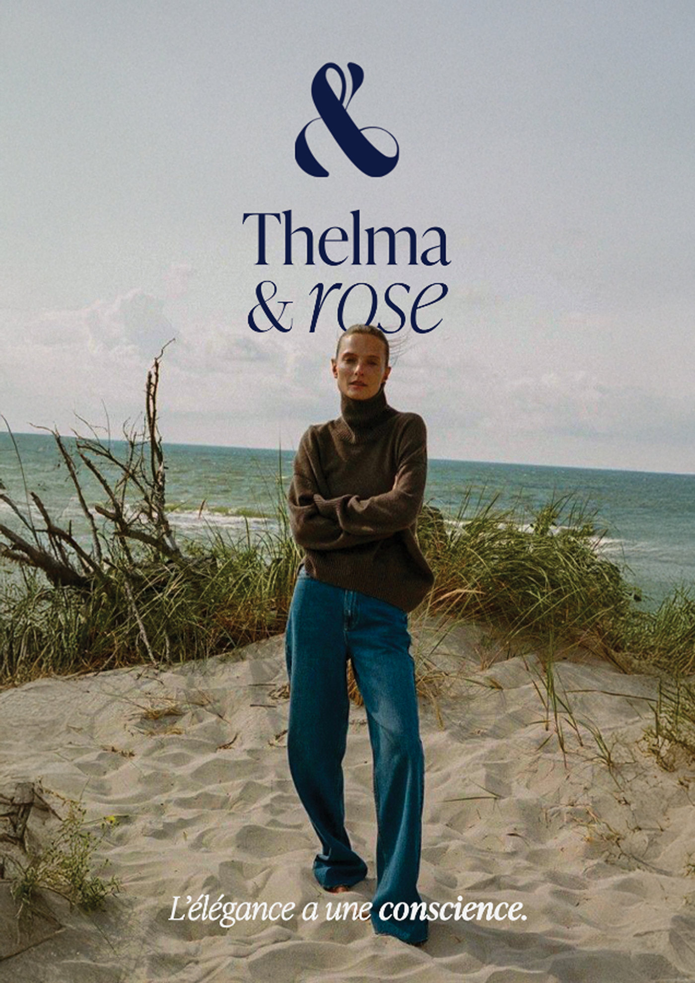 Affiche : une femme en pull marron et jean sur une dune, la mer derrière, logo navy en haut