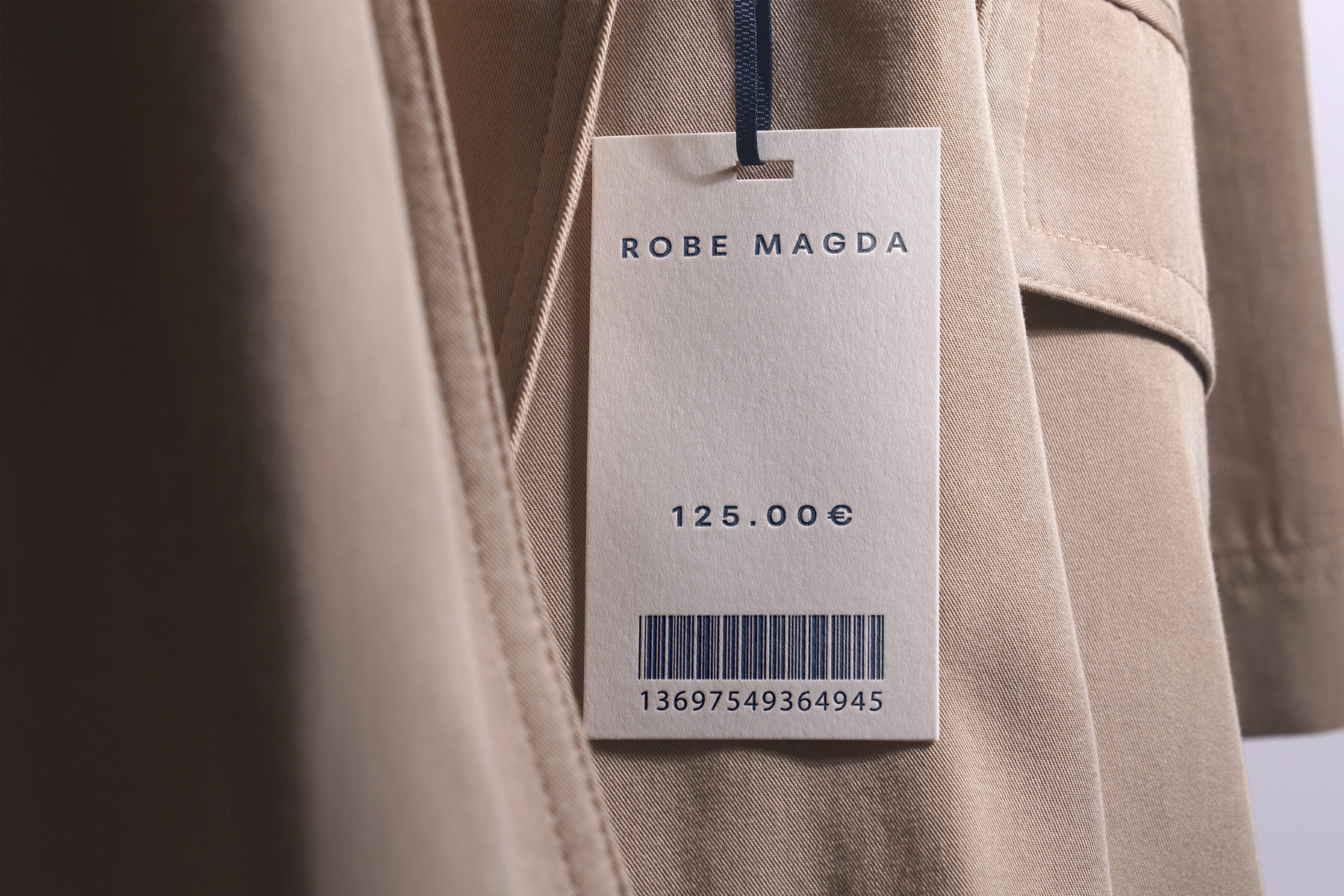 L’étiquette, verso : Robe Magda, 125,00 €, code-barres, accrochée au manteau